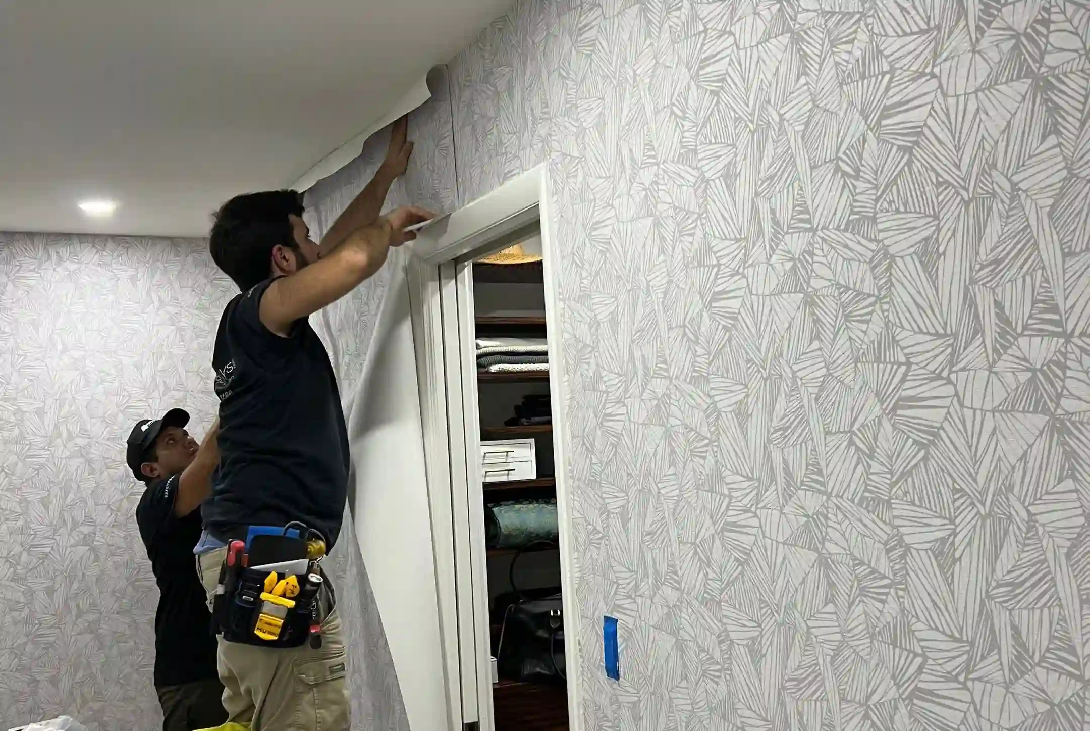 Wallpaper installer aligning a botanical pattern in a Northeast Minneapolis living room