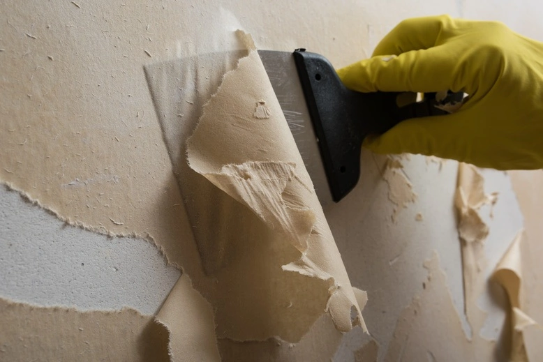 Installer lifting old wallpaper from a Bloomington wall near Normandale Lake