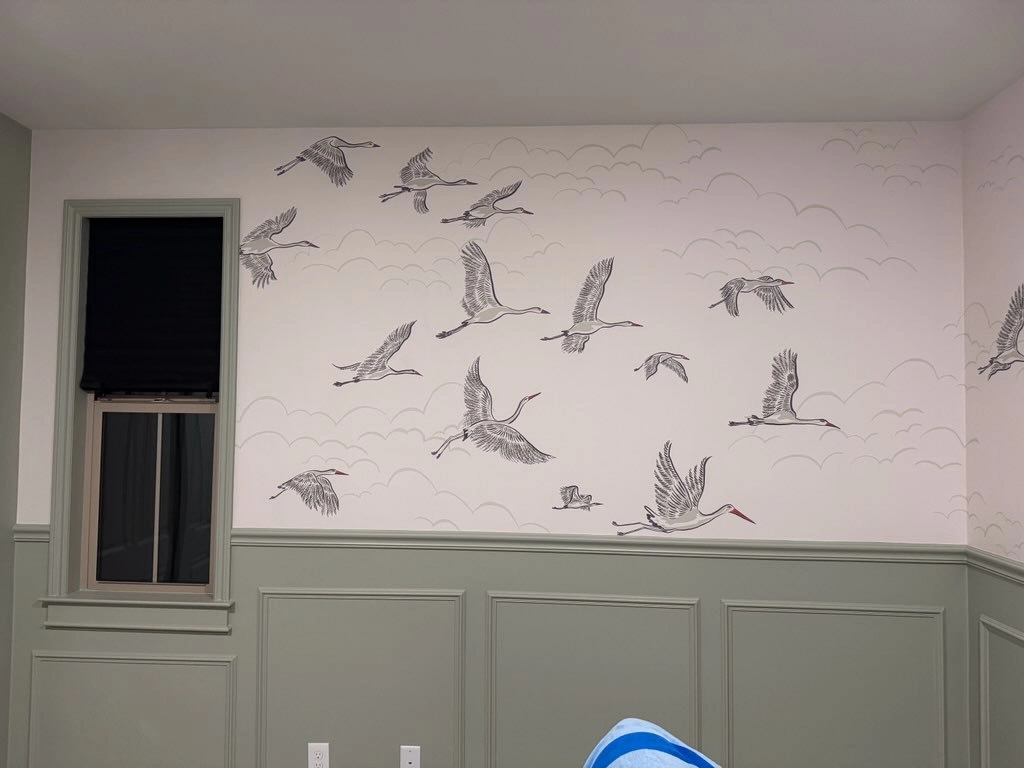 Bird-pattern wallpaper above paneled walls in a Woodbury home